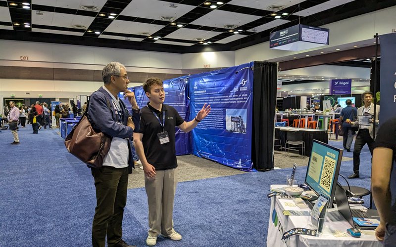 Team member demoing to visitor at booth